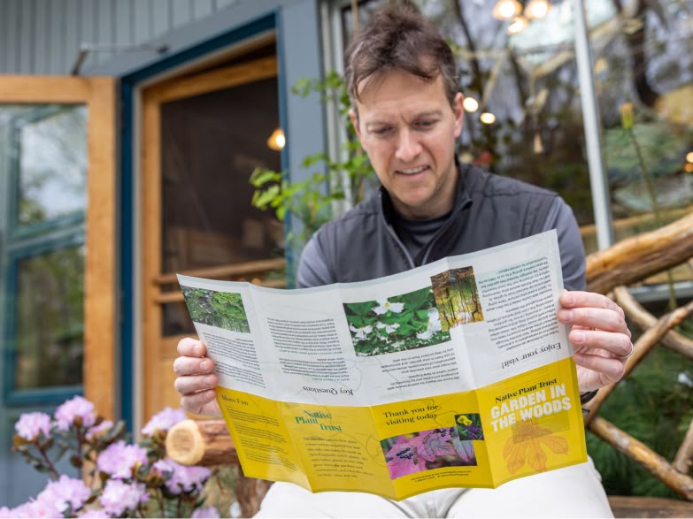 Man reading Garden in the Woods pamphlet